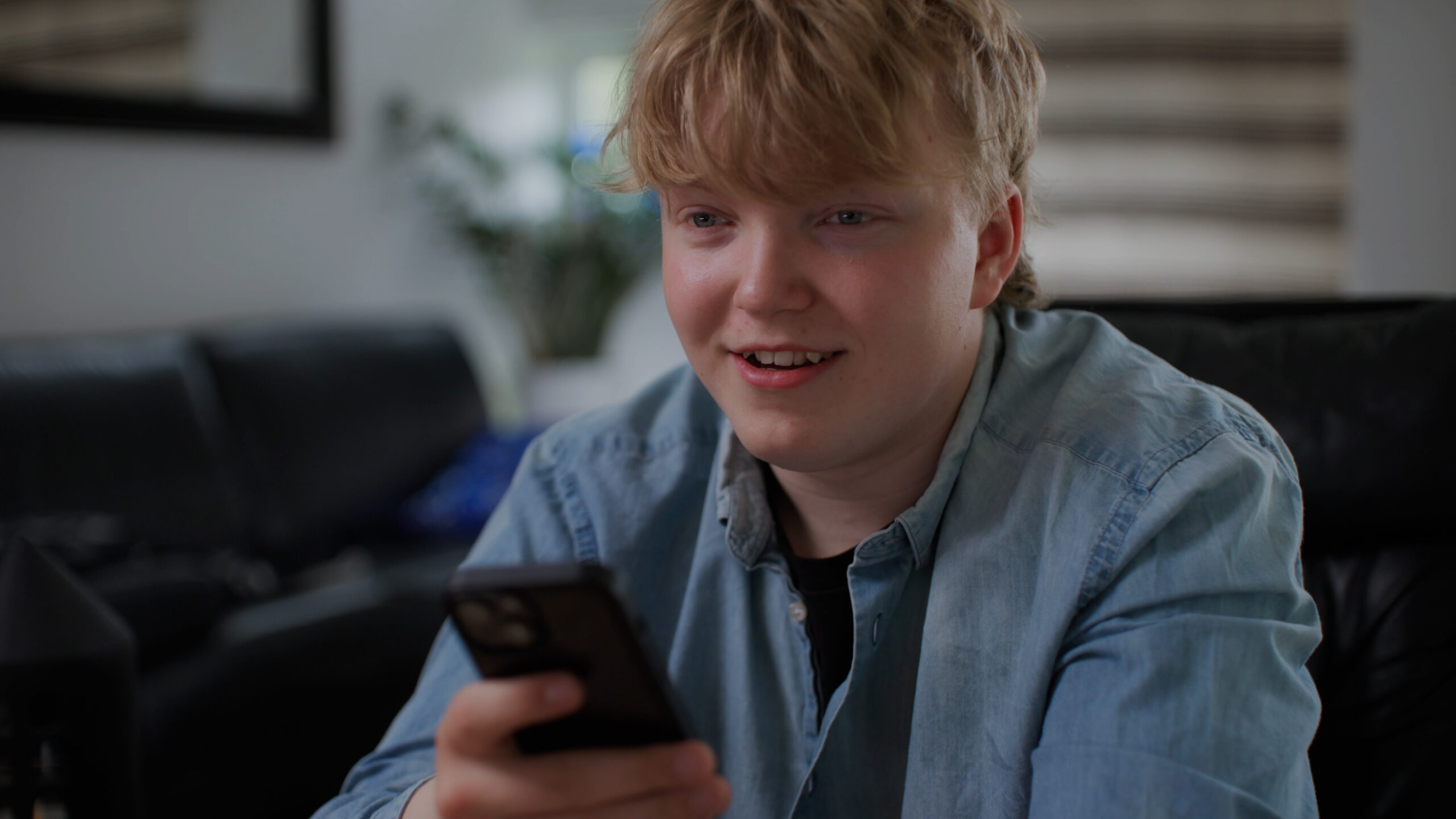 Aaron smiler og holder mobilen sin.